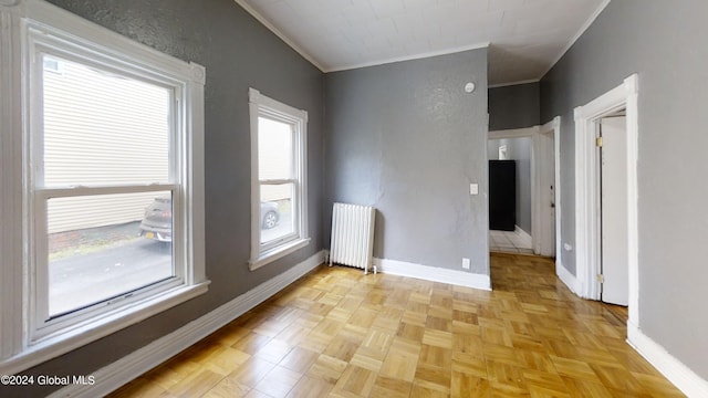 empty room featuring radiator, crown molding, and light parquet flooring