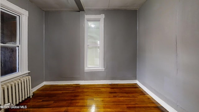 empty room featuring radiator heating unit and dark wood-type flooring