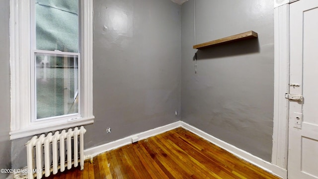 spare room with radiator heating unit and dark hardwood / wood-style floors