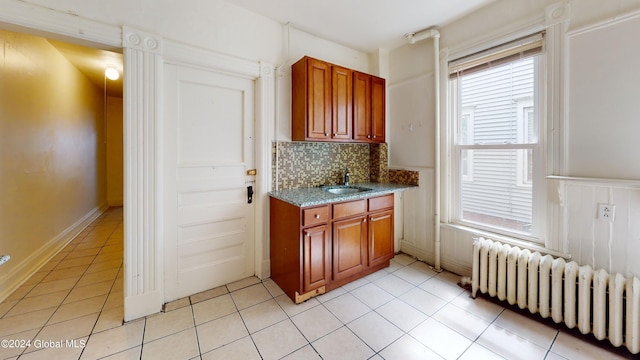 kitchen featuring tasteful backsplash, radiator, sink, and light tile patterned flooring