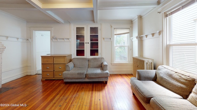 living area with hardwood / wood-style floors, radiator heating unit, beamed ceiling, and ornamental molding