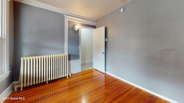 unfurnished room featuring radiator and hardwood / wood-style floors