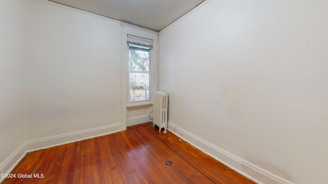 spare room with radiator heating unit and dark wood-type flooring