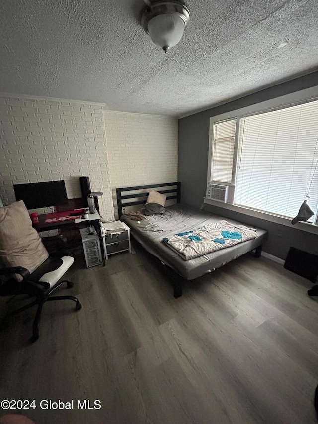 bedroom with hardwood / wood-style flooring, cooling unit, and a textured ceiling