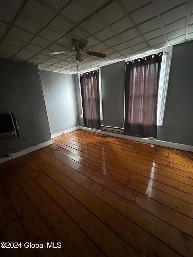 empty room featuring ceiling fan, a drop ceiling, and hardwood / wood-style flooring