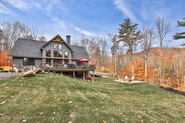 back of property with a lawn, a wooden deck, and a patio