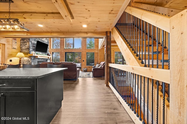 kitchen featuring dark wood-type flooring, hanging light fixtures, wooden walls, beam ceiling, and wood ceiling