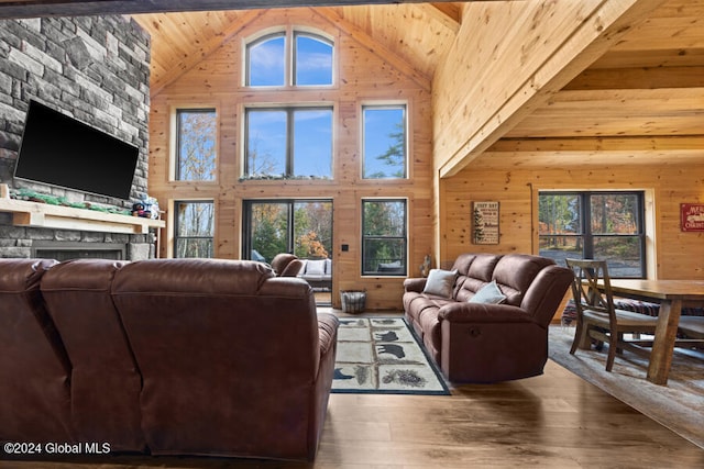 living room with wooden ceiling, high vaulted ceiling, wood walls, a fireplace, and hardwood / wood-style flooring