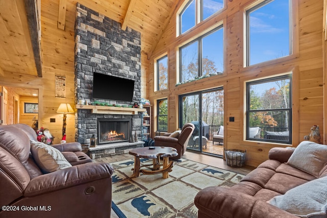 living room with hardwood / wood-style floors, wood walls, high vaulted ceiling, a stone fireplace, and beamed ceiling