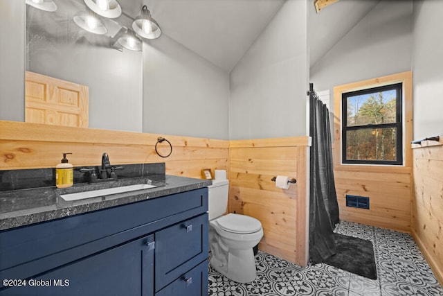 bathroom featuring vanity, vaulted ceiling, tile patterned flooring, toilet, and wood walls