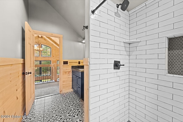 bathroom with a tile shower, vanity, and lofted ceiling