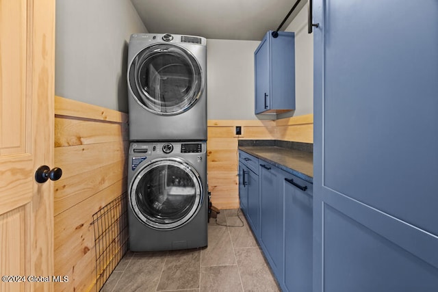 washroom with light tile patterned floors, cabinets, and stacked washer / drying machine