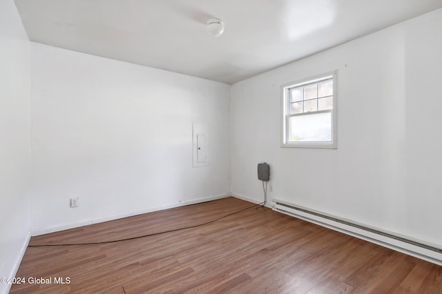 unfurnished room featuring electric panel, wood-type flooring, and a baseboard heating unit