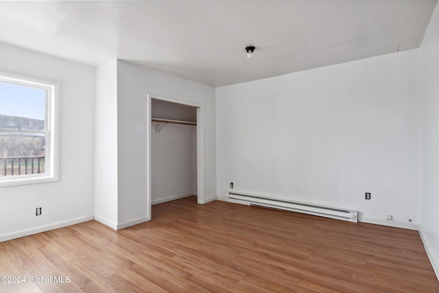 unfurnished bedroom featuring a baseboard radiator, a closet, and light hardwood / wood-style floors