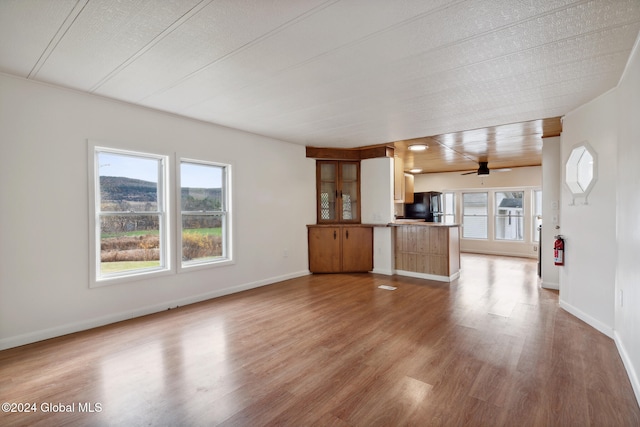 unfurnished living room featuring a textured ceiling, ceiling fan, wood-type flooring, and a wealth of natural light