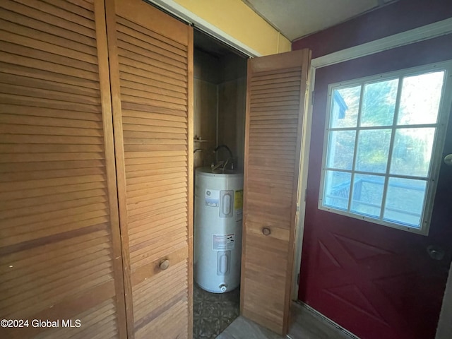 doorway to outside with electric water heater and wooden walls