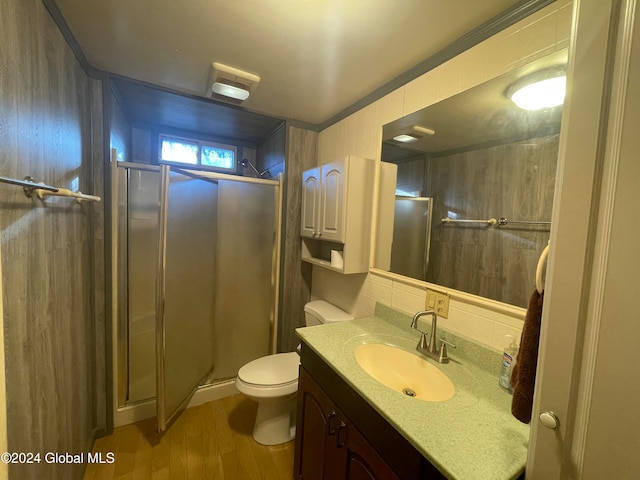 bathroom with toilet, vanity, hardwood / wood-style floors, and a shower with door