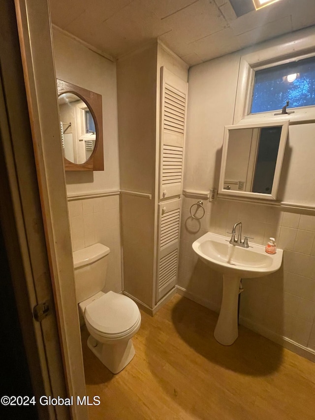 bathroom featuring toilet, sink, tile walls, and wood-type flooring