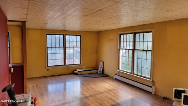 unfurnished room with light hardwood / wood-style floors and a baseboard heating unit