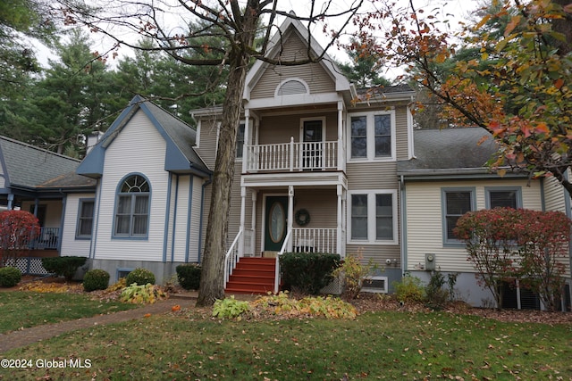 view of front of home featuring covered porch, a front yard, and a balcony