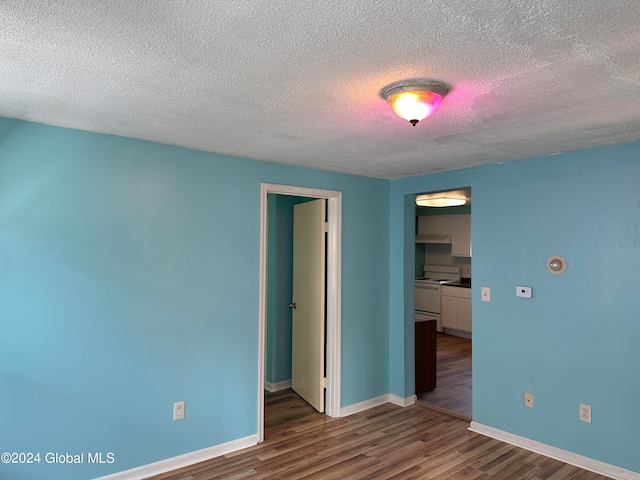 empty room with dark wood-type flooring and a textured ceiling