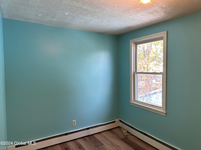 spare room with a baseboard heating unit, wood-type flooring, and a textured ceiling