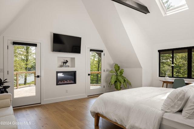 bedroom with access to exterior, light wood-type flooring, and lofted ceiling with skylight