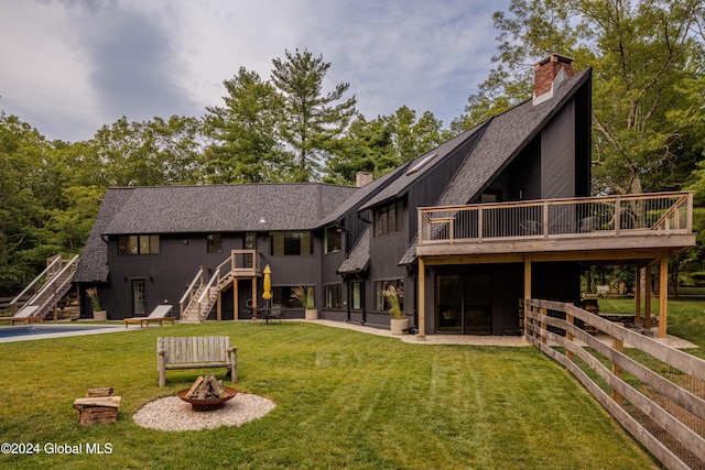 back of house featuring a fire pit, a patio, a yard, and a deck