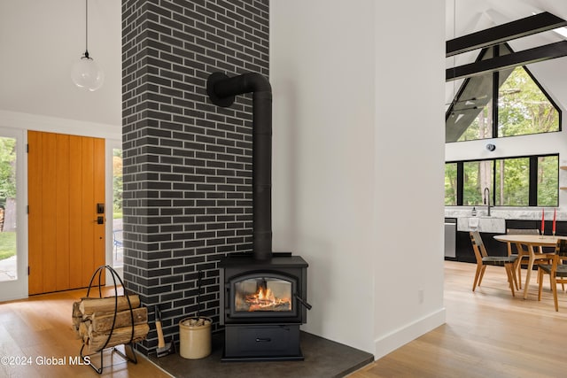 interior details with wood-type flooring, sink, a wood stove, and dishwasher