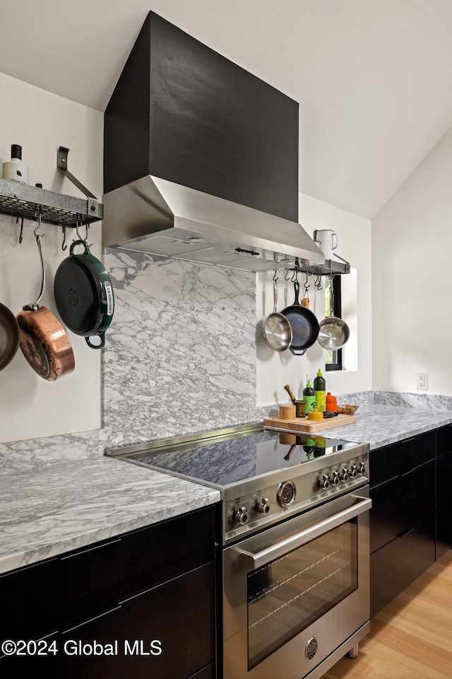 kitchen featuring wall chimney range hood, stainless steel stove, and light hardwood / wood-style floors