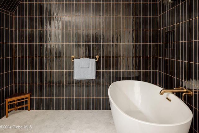 bathroom with a bath, tile patterned floors, and tile walls