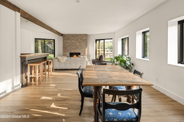 dining space featuring a brick fireplace, plenty of natural light, and light hardwood / wood-style flooring