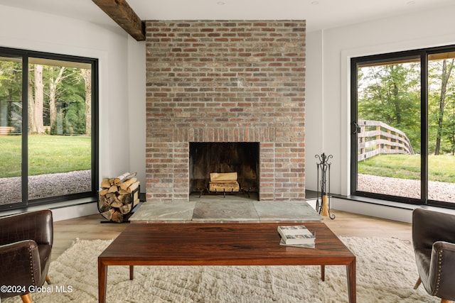 living room with a brick fireplace, a wealth of natural light, and light hardwood / wood-style floors