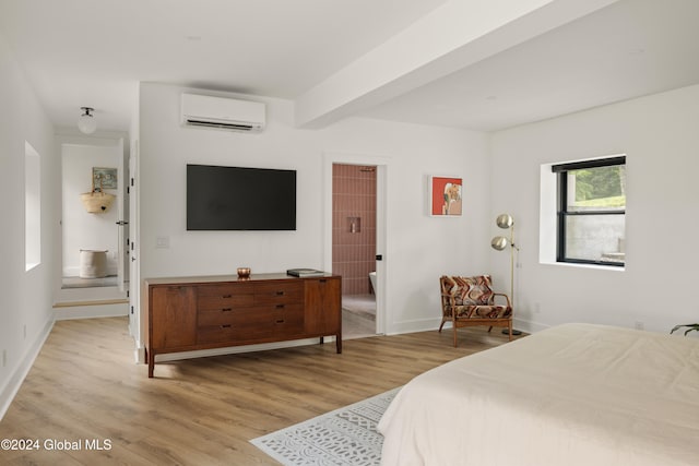 bedroom with light hardwood / wood-style floors, beamed ceiling, and an AC wall unit