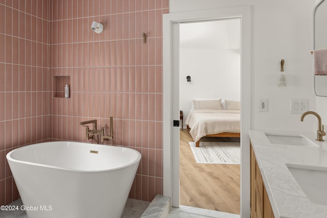 bathroom featuring sink, tile walls, wood-type flooring, and a tub