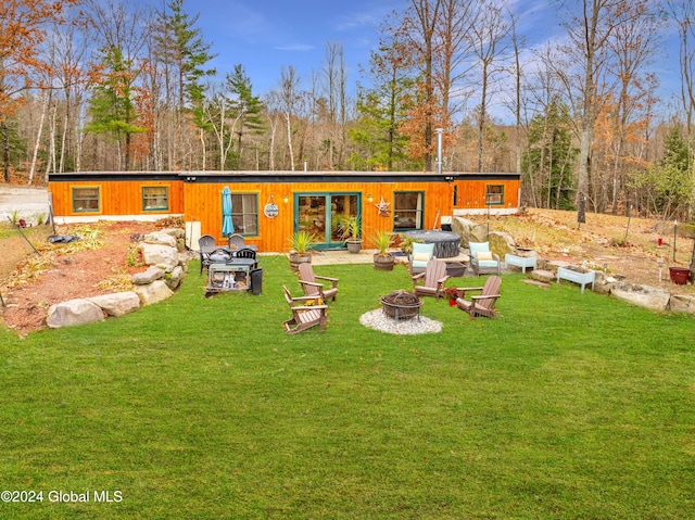 rear view of property featuring a yard and a fire pit