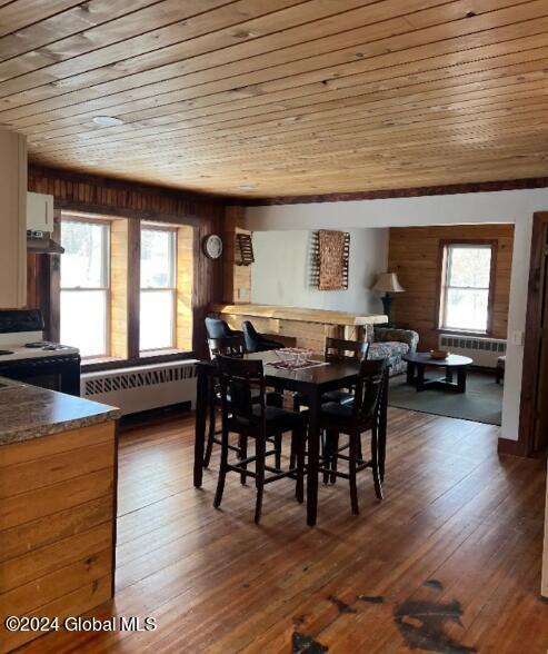 dining room with dark hardwood / wood-style flooring, radiator heating unit, and wooden ceiling