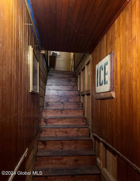 stairway featuring wood walls and wood ceiling