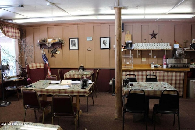 dining area featuring carpet floors and wooden walls