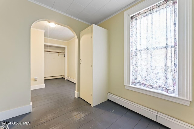 hallway with baseboard heating, crown molding, and dark wood-type flooring