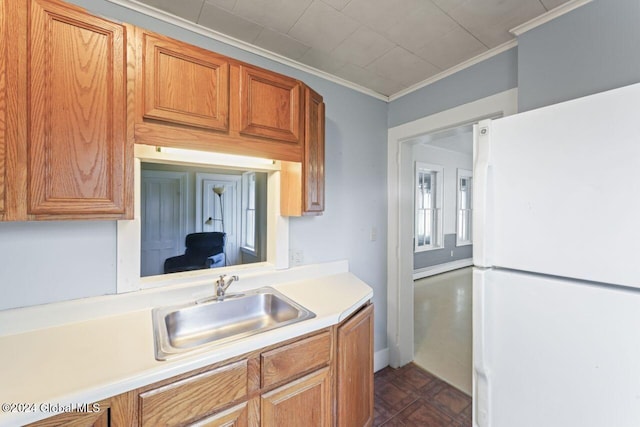 kitchen featuring white fridge, crown molding, and sink