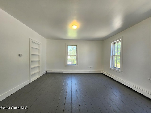 spare room with dark wood-type flooring and a baseboard heating unit