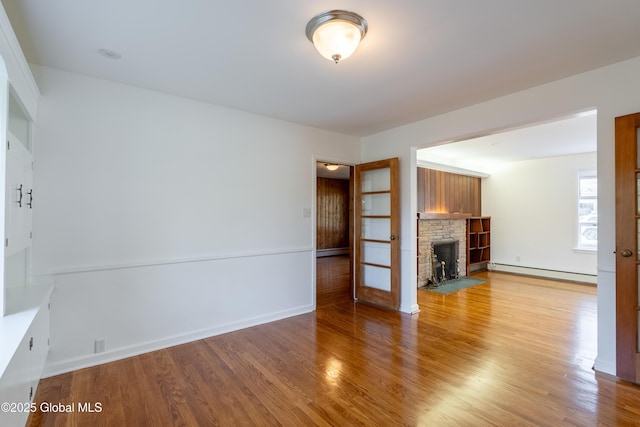 1258 Hawthorn Rd, Niskayuna, NY 12309 - unfurnished living room featuring a baseboard radiator, a stone fireplace, wood finished floors, baseboards, and baseboard heating