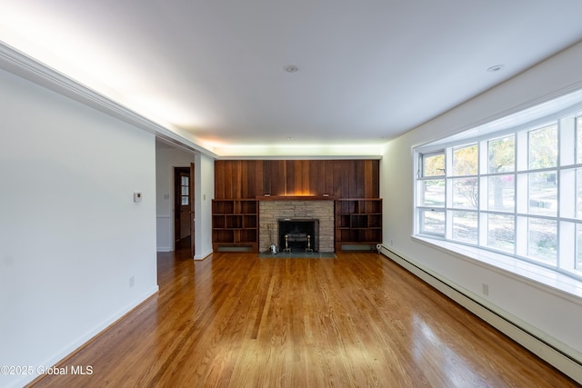 1258 Hawthorn Rd, Niskayuna, NY 12309 - unfurnished living room featuring baseboard heating, wood finished floors, a stone fireplace, and baseboards
