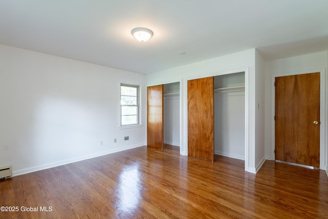 1258 Hawthorn Rd, Niskayuna, NY 12309 - unfurnished bedroom featuring two closets, wood finished floors, baseboards, and a baseboard heating unit