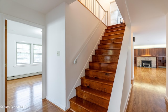 1258 Hawthorn Rd, Niskayuna, NY 12309 - staircase featuring a baseboard heating unit, wood finished floors, a fireplace, and baseboards