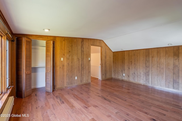 1258 Hawthorn Rd, Niskayuna, NY 12309 - unfurnished bedroom with lofted ceiling, wood walls, wood finished floors, a closet, and a baseboard heating unit