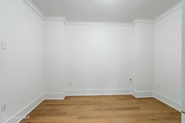 empty room with baseboards, crown molding, and light wood-style floors