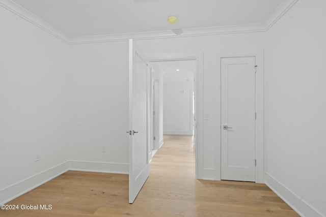 interior space featuring crown molding, baseboards, and light wood finished floors