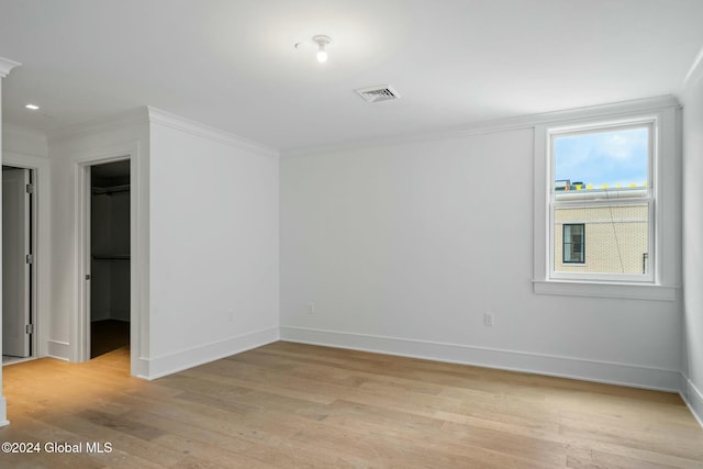 unfurnished bedroom with light wood-type flooring, visible vents, and ornamental molding